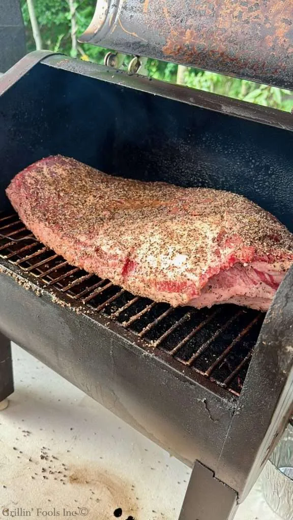 Beef brisket with a coarse rub on a barbecue smoker/grill.