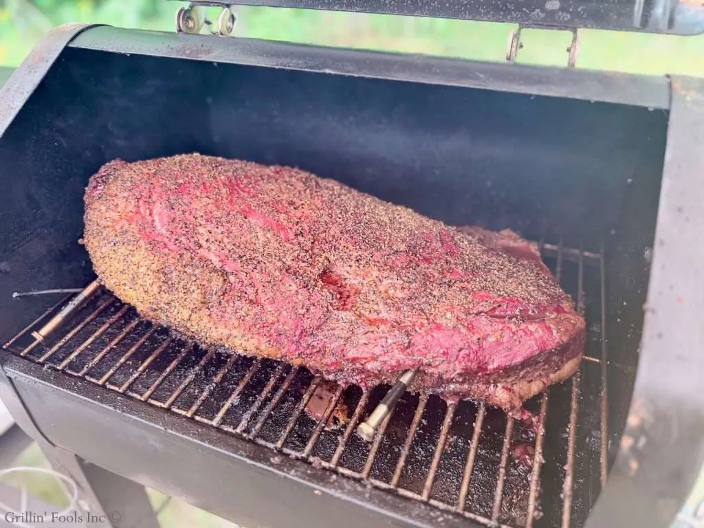 Smoked beef brisket with a crusty spice rub inside a smoker