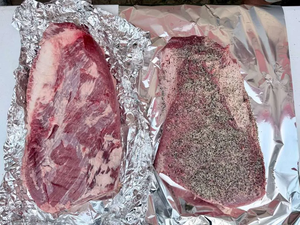 Two beef briskets, one slathered in seasoning and the other bare, both on aluminum foil. The seasoned one will have the dry brine overnight, the other will not