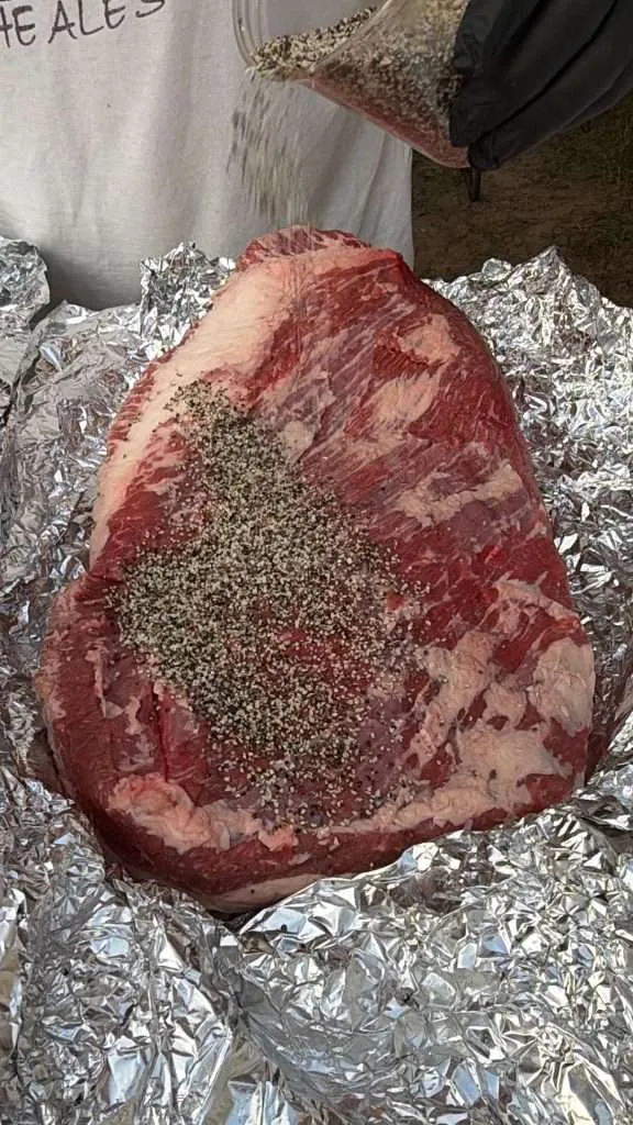 Seasoning a whole, raw beef brisket with SPG seasoning