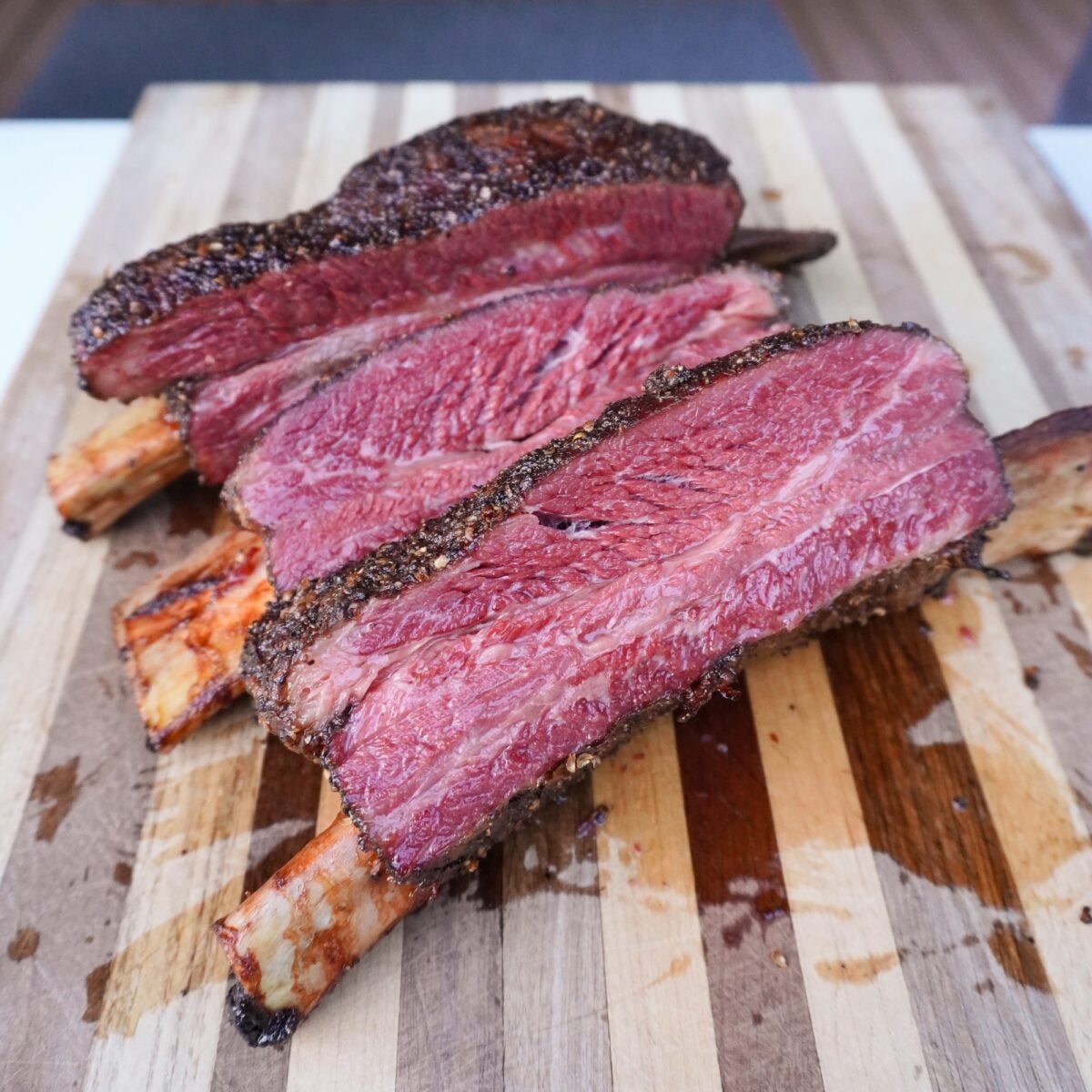 Sliced Smoked Pastrami Beef Ribs on a cutting board.