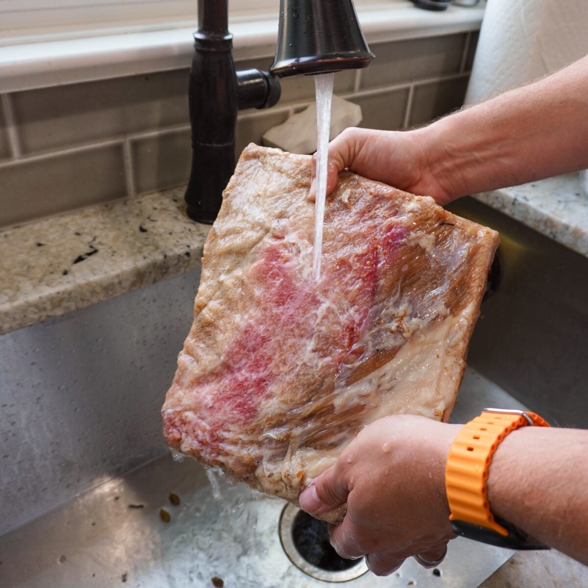 Rinsing brined ribs in the kitchen sink.