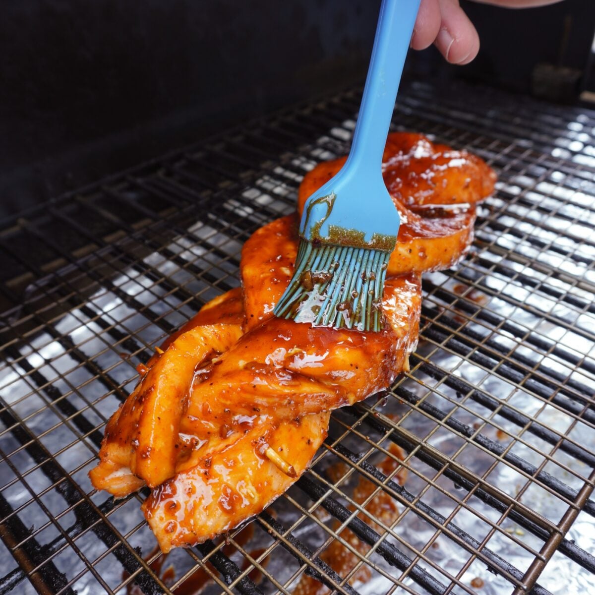 Glazing the smoked braided salmon with the sweet honey garlic glaze.