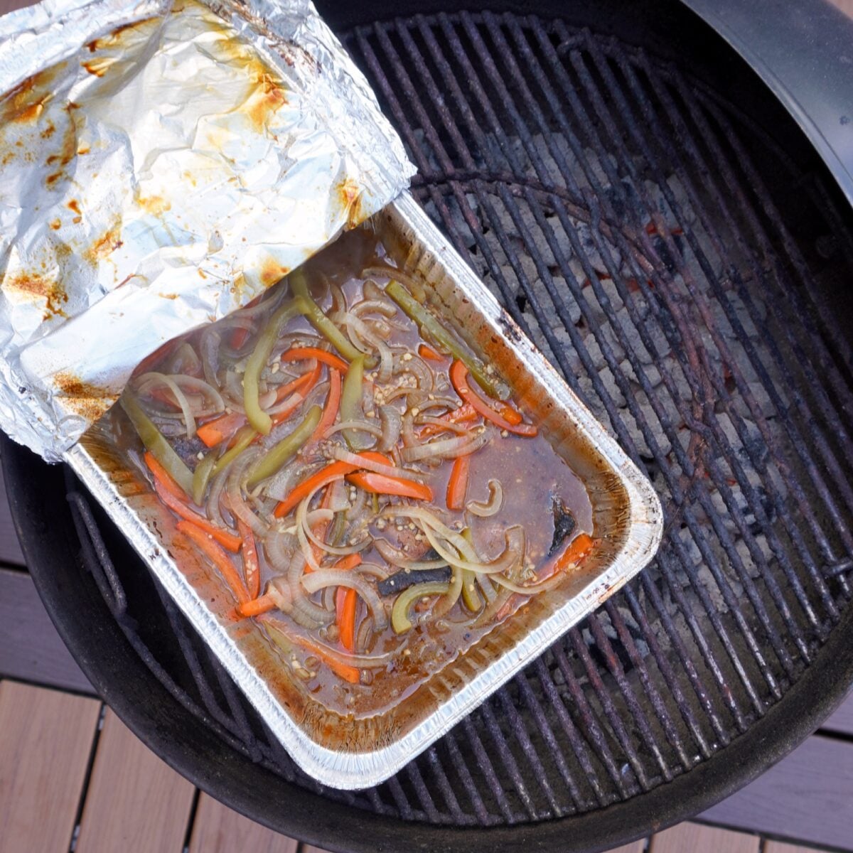 Braised pork steaks in aluminum pan over the grill.