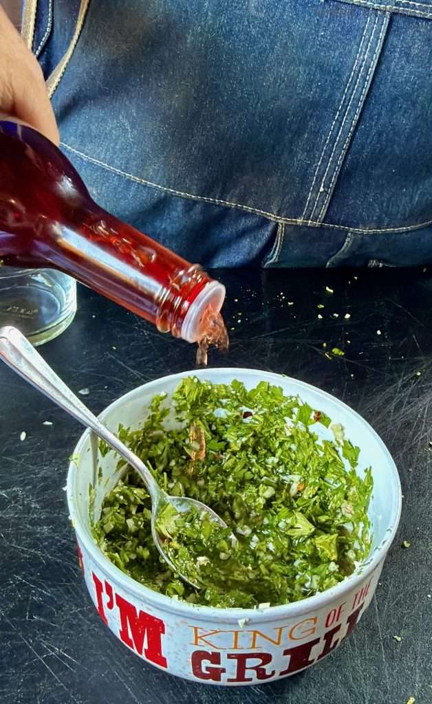 Pouring a little extra red wine vinegar into my chimichurri