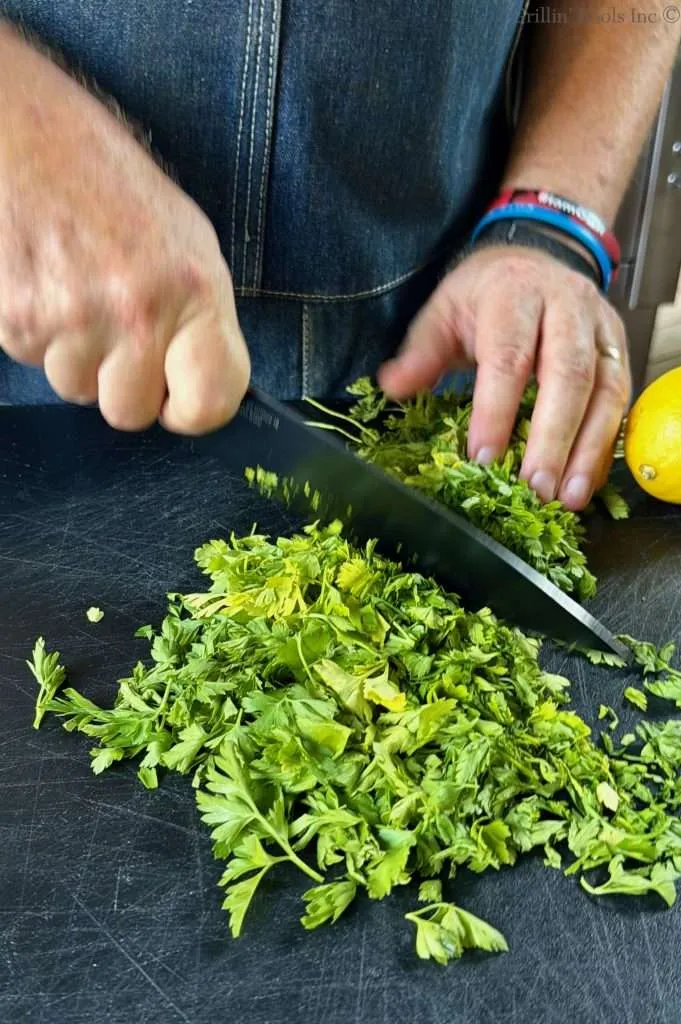 Chopping fresh parsley on a black cutting board