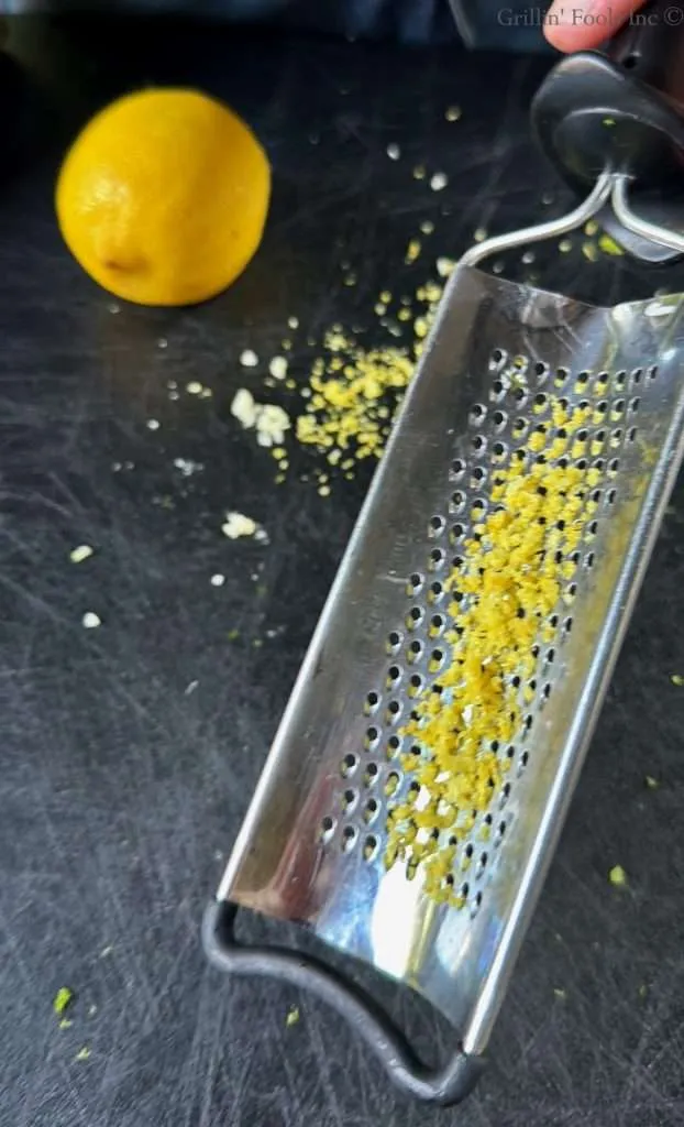Zest of a lemon on the back of a cheese grater with the grated lemon nearby