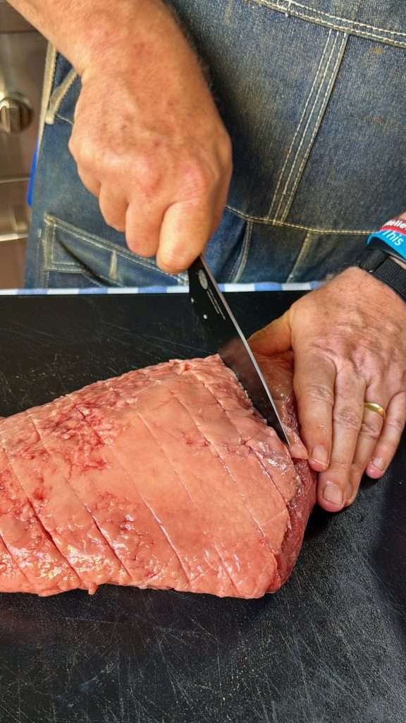 Carving a criss cross pattern in the fat cap of a picaña roast