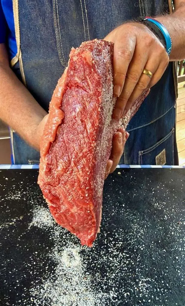 Getting ready to dab the skinny, flat edge of the picanha roast in the excess seasoning on the cutting board