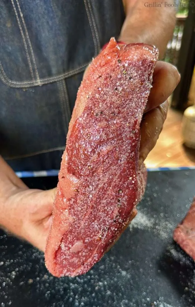 The skinny, flat edge of the picanha roast after being dabbed in the the excess seasoning on the cutting board.