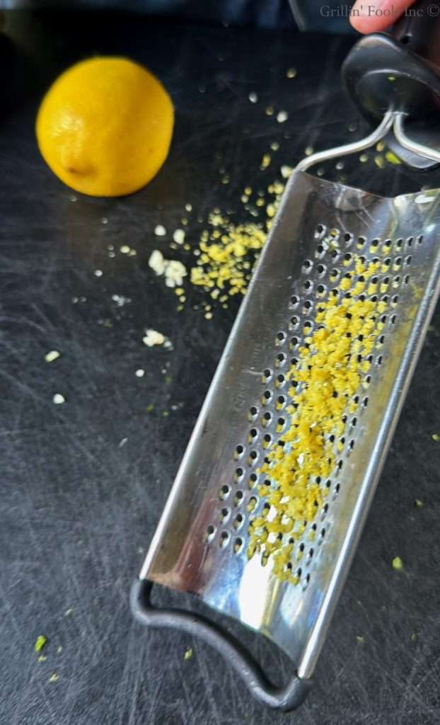 Zest of a lemon on the back of a cheese grater with the grated lemon nearby
