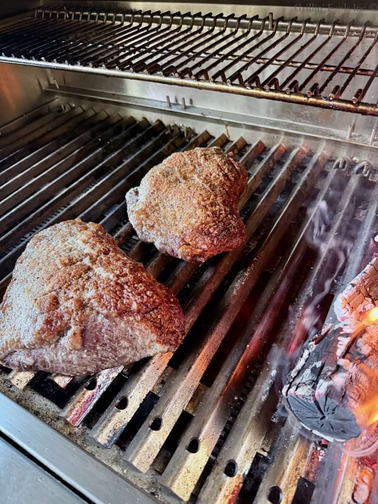 Two picanha roasts with the tops closest to the fire browned a bit.