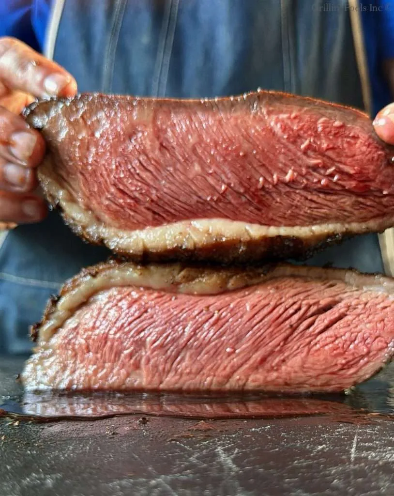 A picanha sliced in half and photographed from the side where both edge cuts are displayed, stacked on top of each other