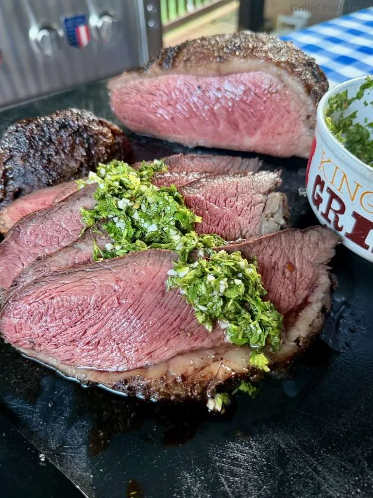 Medium Rare picanha sliced with fresh chimichurri spooned over the top