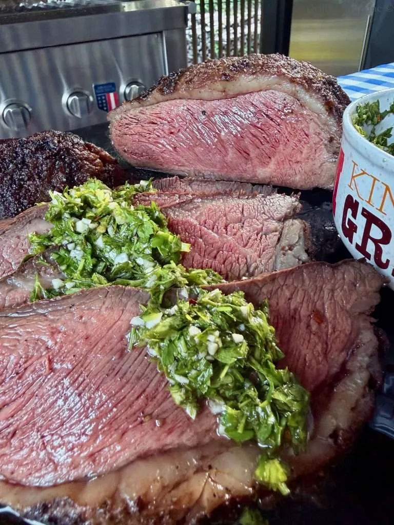 Sliced Picanha Roast with chimichurri spooned over the top