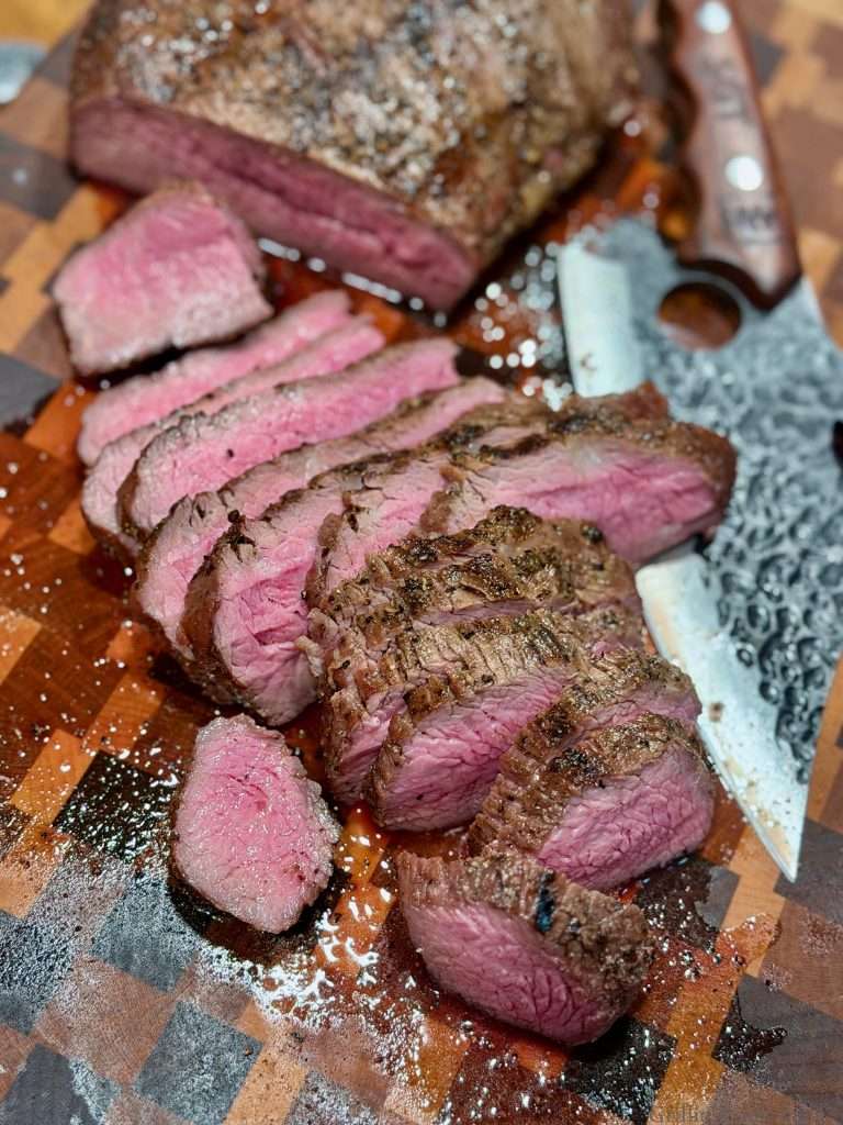 Sliced tri tip, on a cutting board with a wicked knife nearby