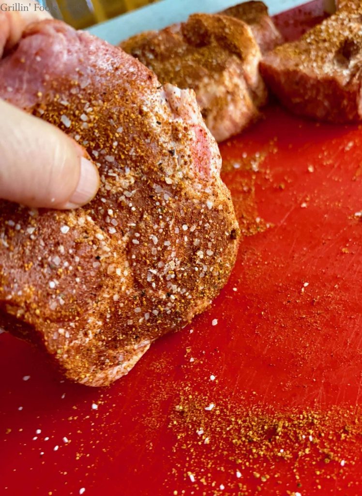 Dabbing the edges of the pork collar throught he excess seasoning on the cutting board.