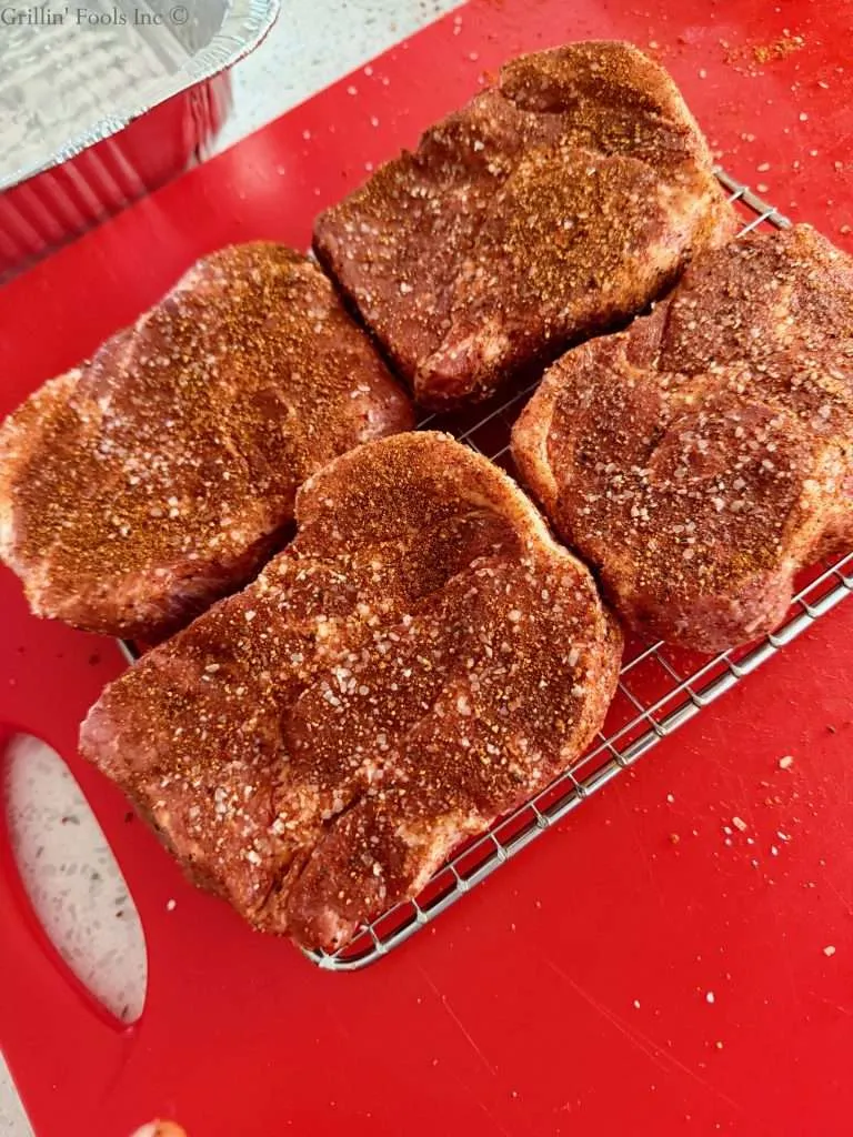 Four seasoned pork collars on a cookie cooling rack