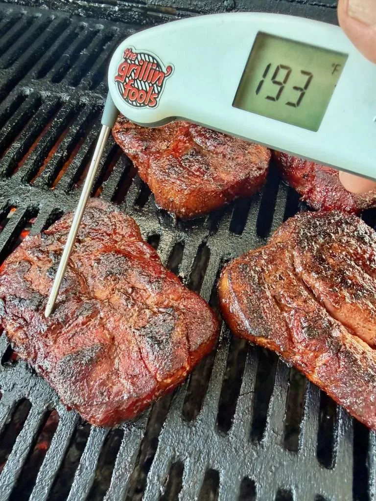 A probe thermometer reading 193F on a charcoal grill