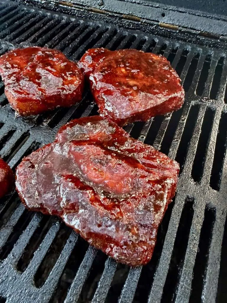 Sauced up pork collars on a charcoal grill