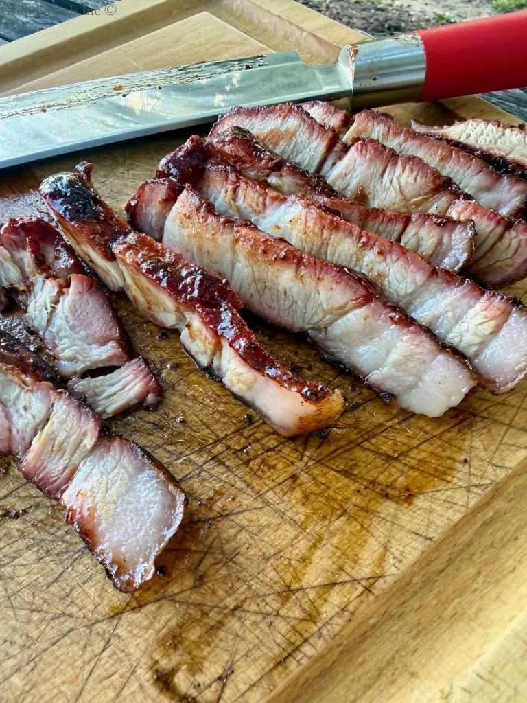 Sliced, juicy, pork collar on a wooden cutting board