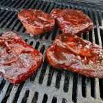 Four sauced pork collars on a charcoal grill