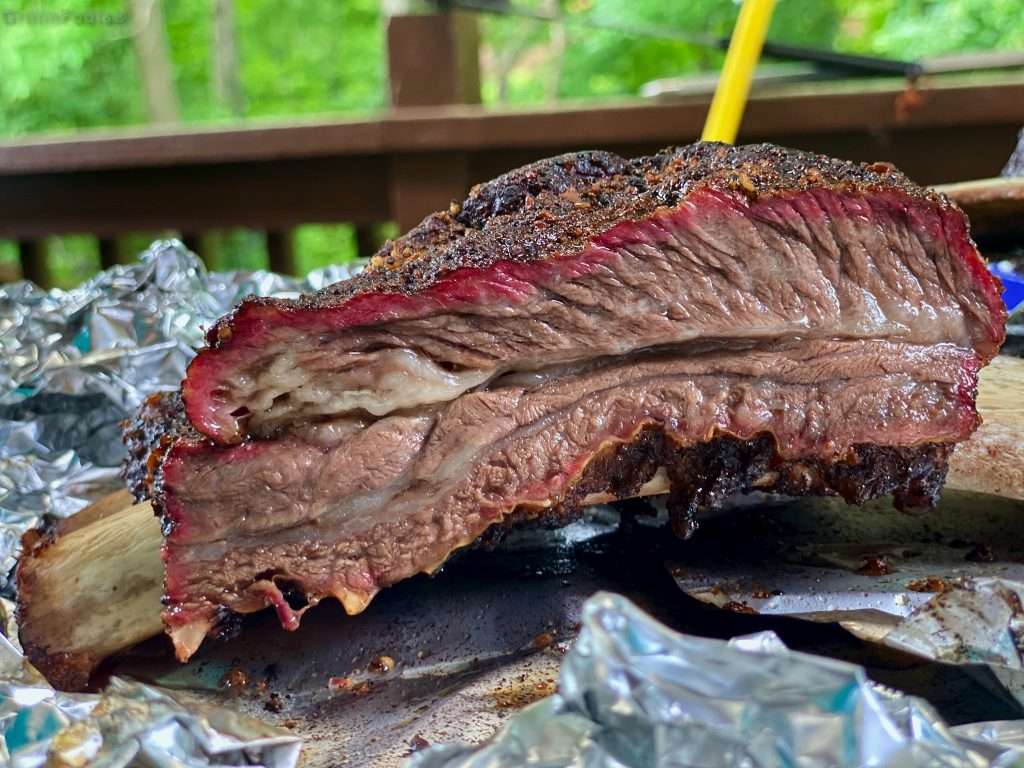 A beef rib carved off a slab with a pronounced smoking ring and flavor bark, on a crumpled sheet of aluminum foil A beef rib carved off a slab with a pronounced smoking ring and flavor bark, on a crumpled sheet of aluminum foil