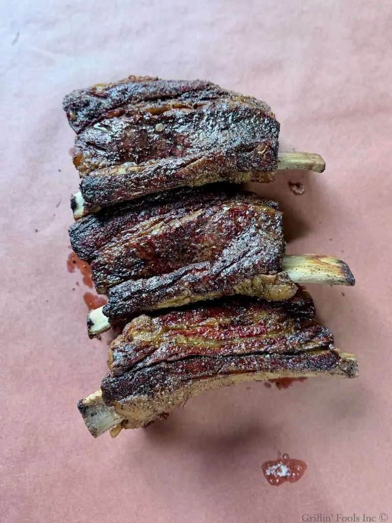 Three beef ribs, lined up on a sheet of butcher paper