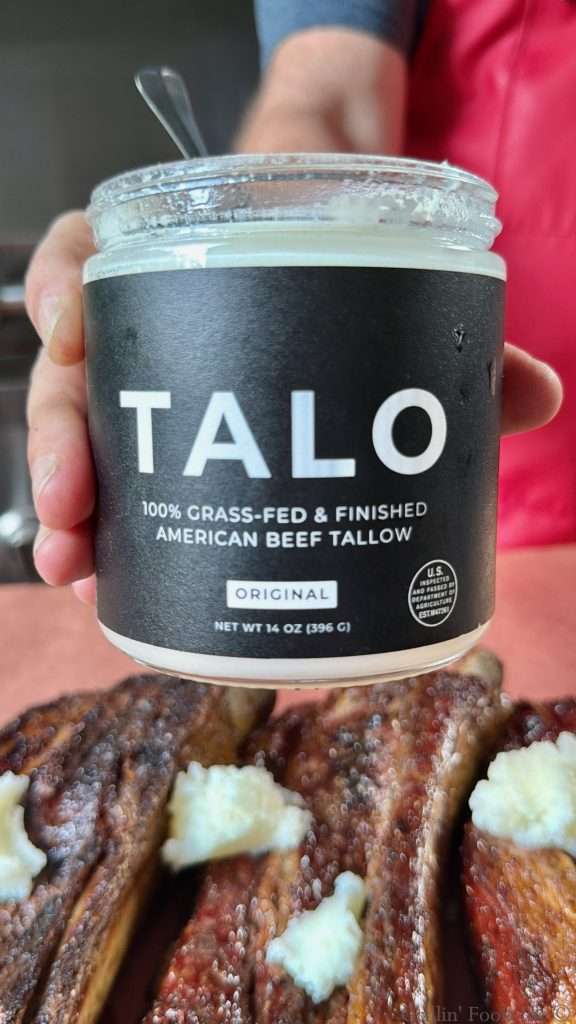 A jar of Talo beef tallow over some tallowed beef ribs on peach butcher paper