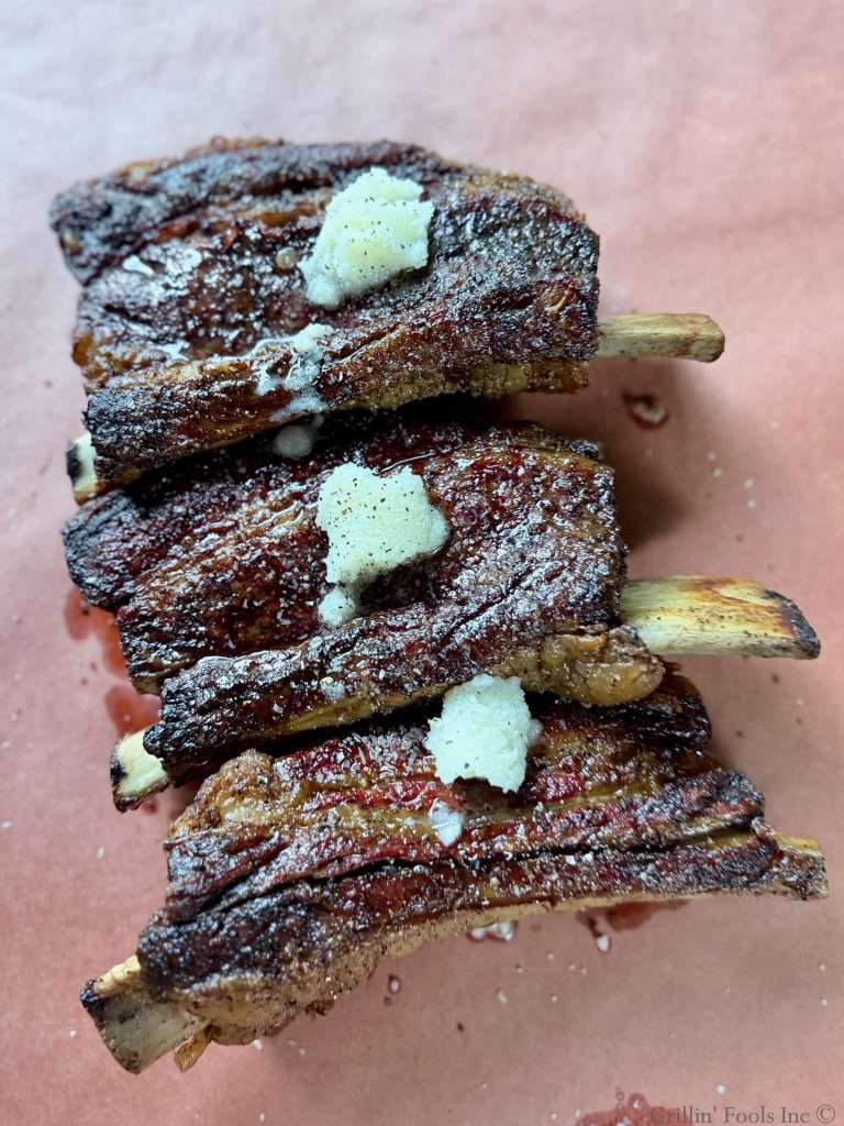 Seasoned beef ribs with three tablespoons of beef tallow on top on a sheet of butcher paper