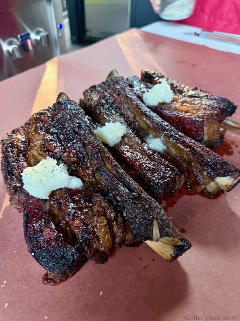 Seasoned beef ribs with three tablespoons of beef tallow on top on a sheet of butcher paper