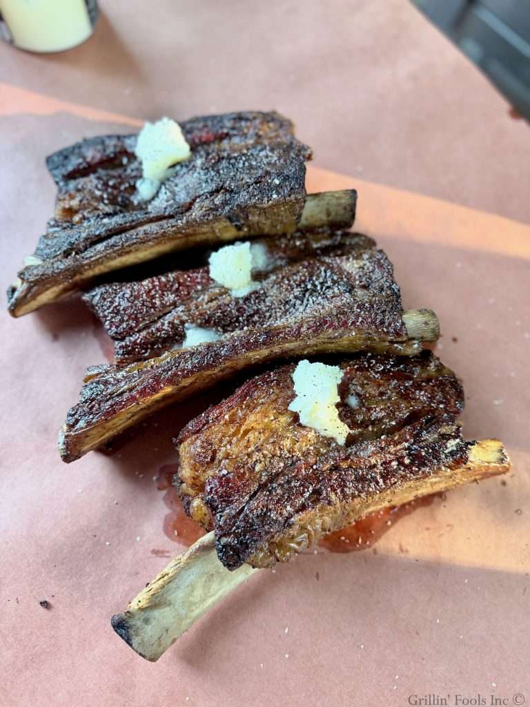 Seasoned beef ribs with three tablespoons of beef tallow on top on a sheet of butcher paper