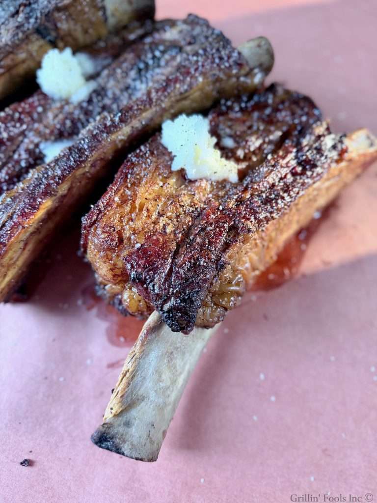 Seasoned beef ribs with three tablespoons of beef tallow on top on a sheet of butcher paper
