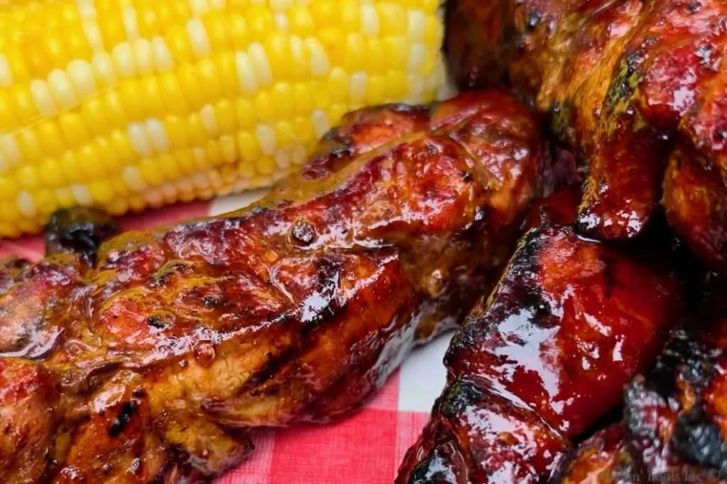 Saucy country style ribs in front of some bright yellow corn on the cob