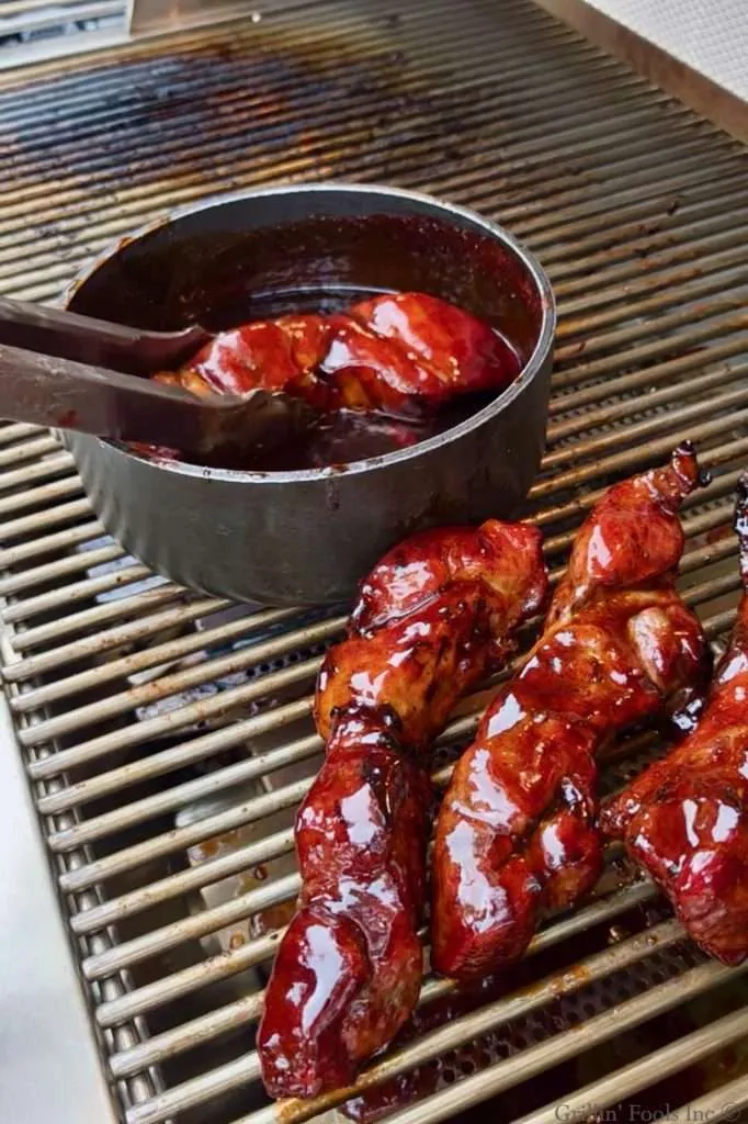 A country rib dunked in a sauce pan full of BBQ sauce