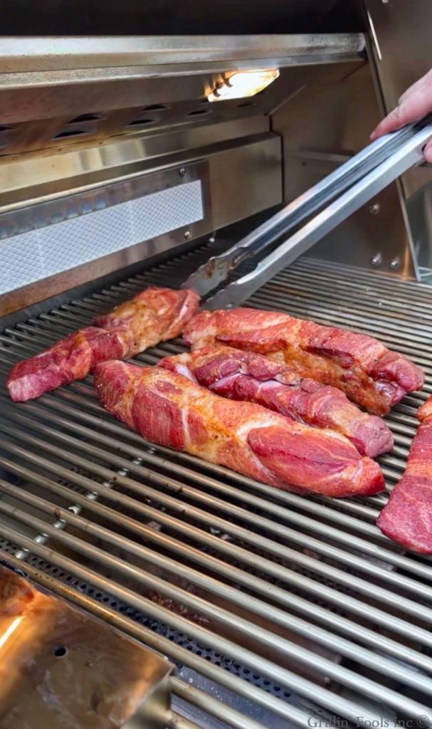 Raw, seasoned country style ribs placed on the cool side of a gas grill