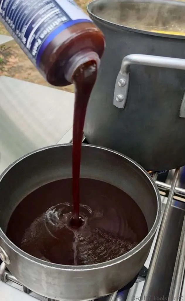 BBQ sauce pouring into a sauce pan over a side burner of a grill