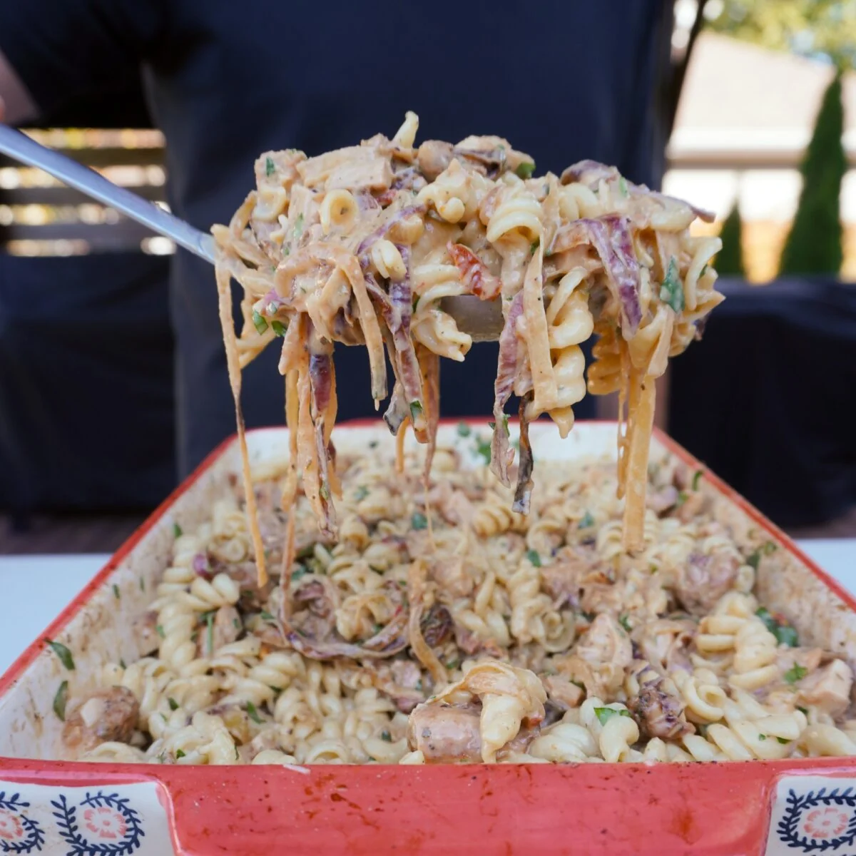 Ladle holding scoped up Caramelized Onion and Chicken Pasta.