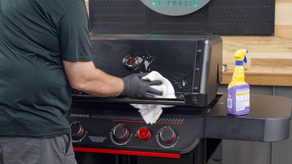 Wiping sticker residue off the Weber Genesis E-330 Stealth lid with cleaner