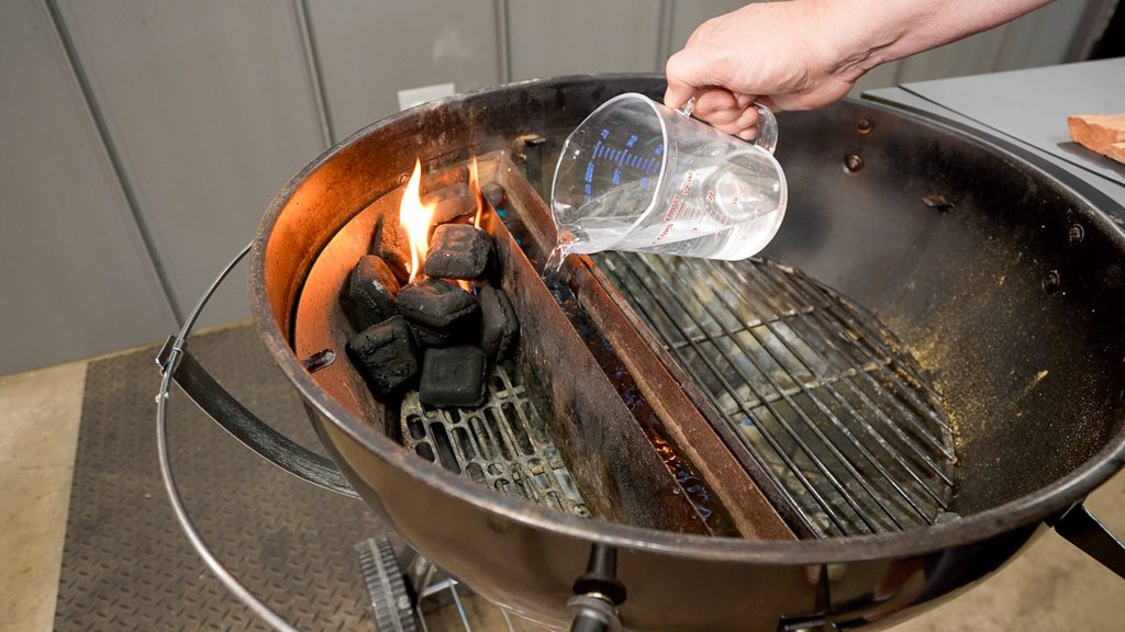 Filling the water reservoir on a Slow 'N Sear basket in a kettle