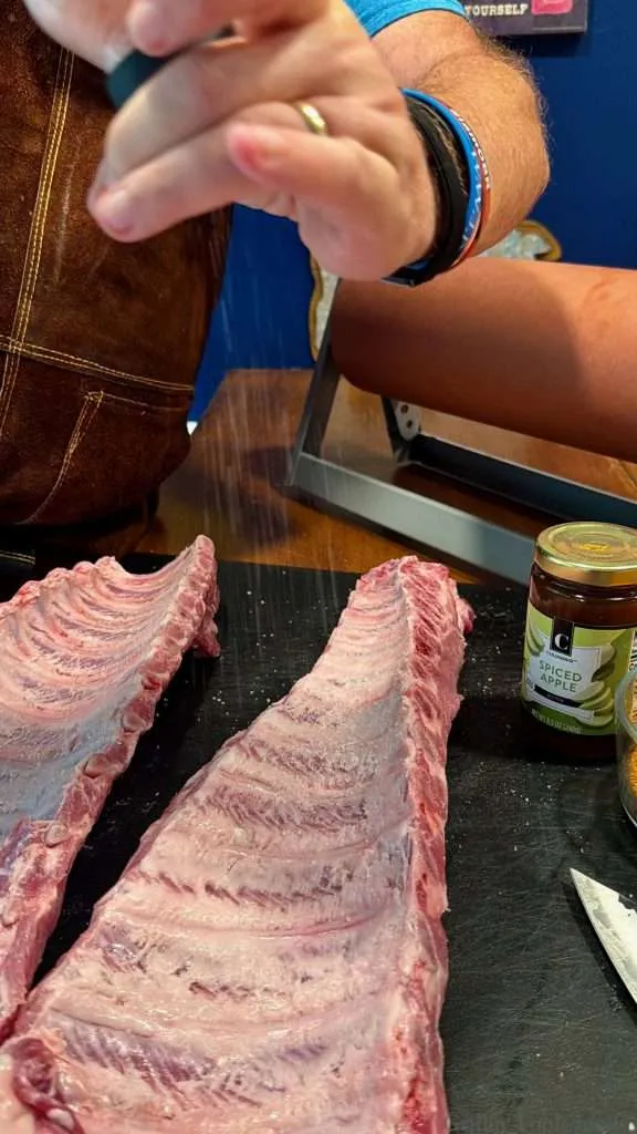 Seasoning a slab of baby back ribs with coarse ground salt