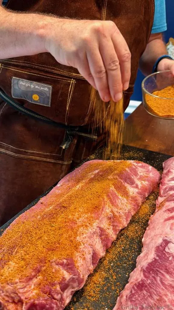 Seasoning the meat side of a slab of ribs with a BBQ rub